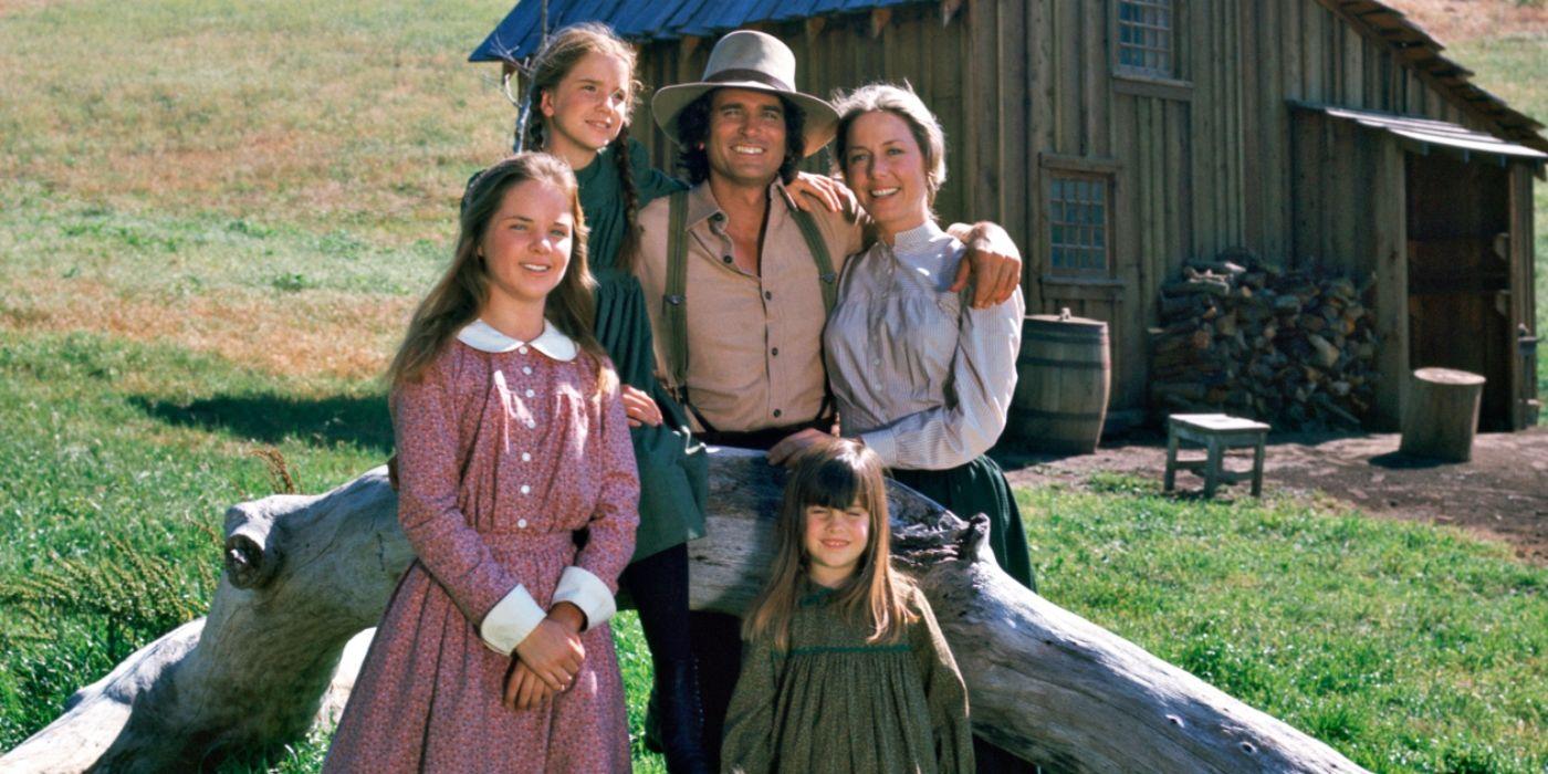 The Ingalls family from 'Little House on the Prairie' posed, smiling in front of their house.