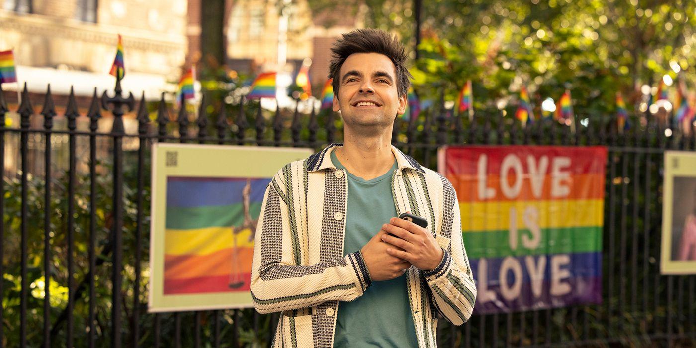 Drew Tarver stands in front of a love is love sign and looks elated in a scene from The Other Two